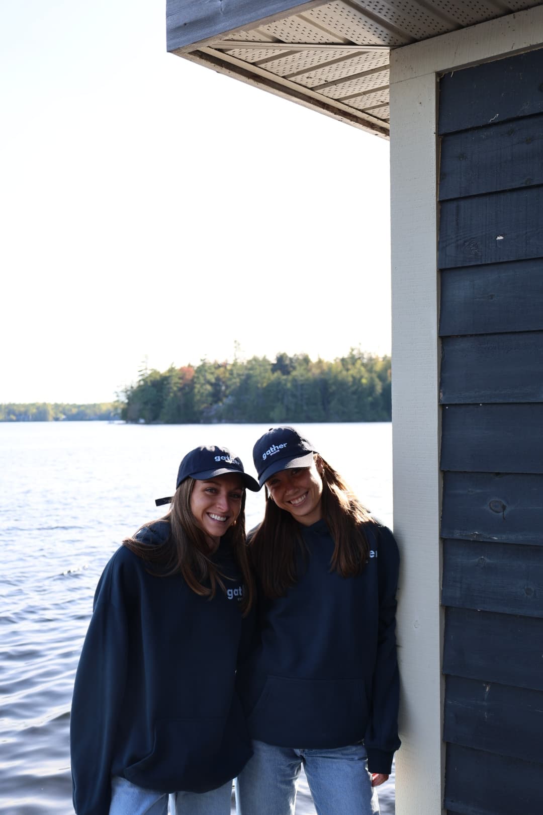 Gather founders smiling together by the boathouse in matching gather hats